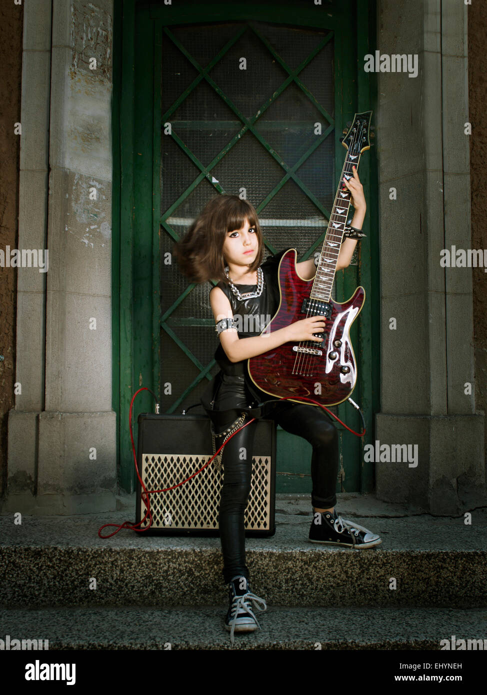 Ragazza vestita come una rock star a suonare la chitarra Foto Stock