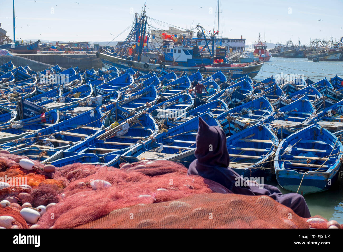 Barche da pesca e uomo in abito tradizionale nel porto di Essaouira, Marocco, Africa del Nord Foto Stock