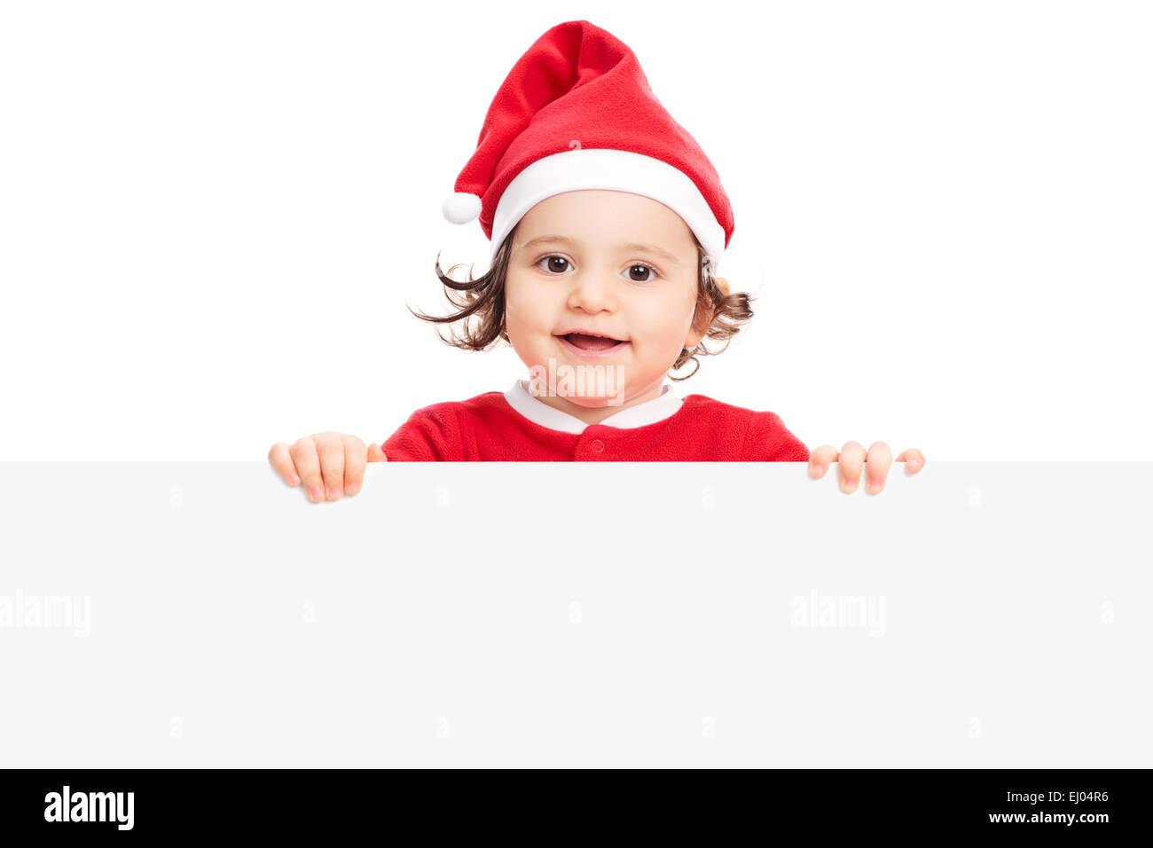 Adorabile bambina con Santa hat in posa dietro un pannello vuoto isolato su sfondo bianco Foto Stock