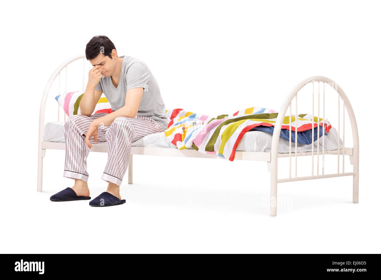 Triste uomo seduto su un letto e contemplando isolati su sfondo bianco Foto Stock