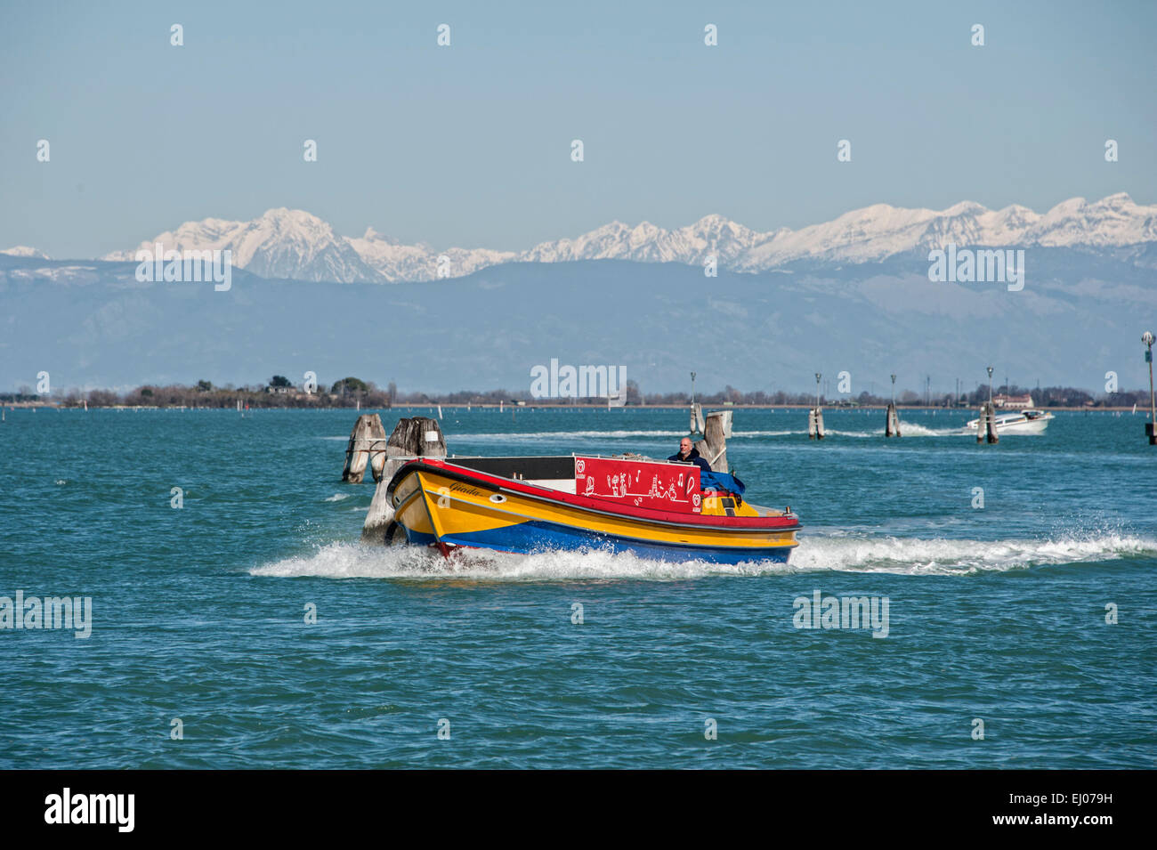 Barca colorato nella laguna veneziana con coperta di neve Dolomiti in background. Foto Stock