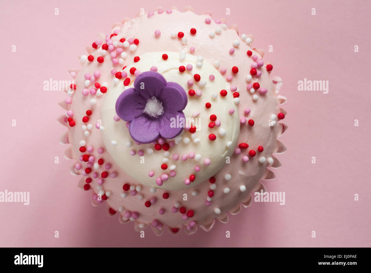 Tesco con amore di fragole e panna tortina con fiore in cima isolata su sfondo rosa Foto Stock