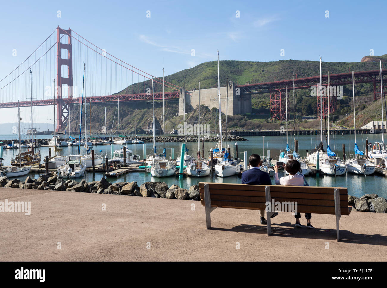 Turisti asiatici, seduti su una panchina, Travis Marina, baia a ferro di cavallo, Fort Baker, Sausalito, Marin County, California Foto Stock