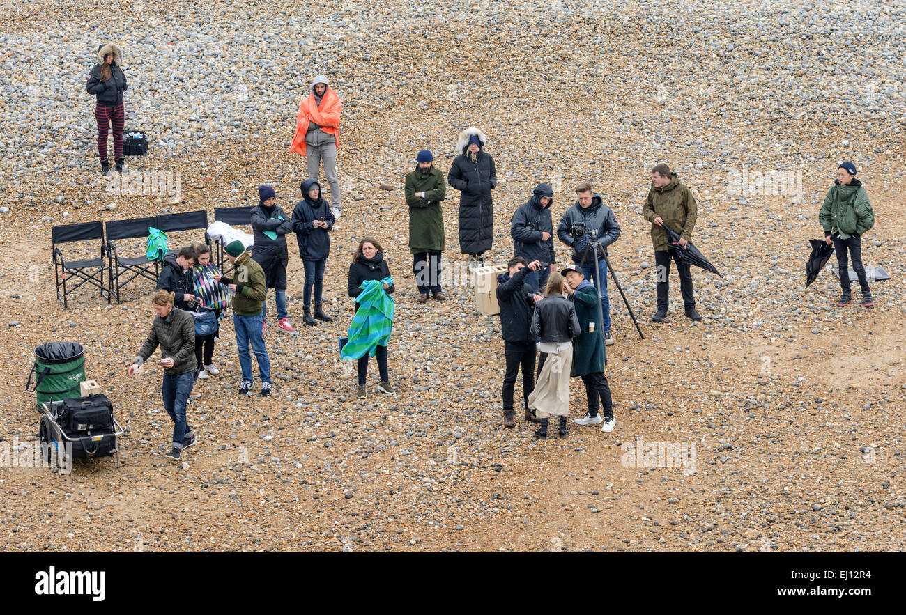 Gruppo del personale e un modello femminile montato su una spiaggia per un professionale servizio fotografico nel Regno Unito. Foto Stock