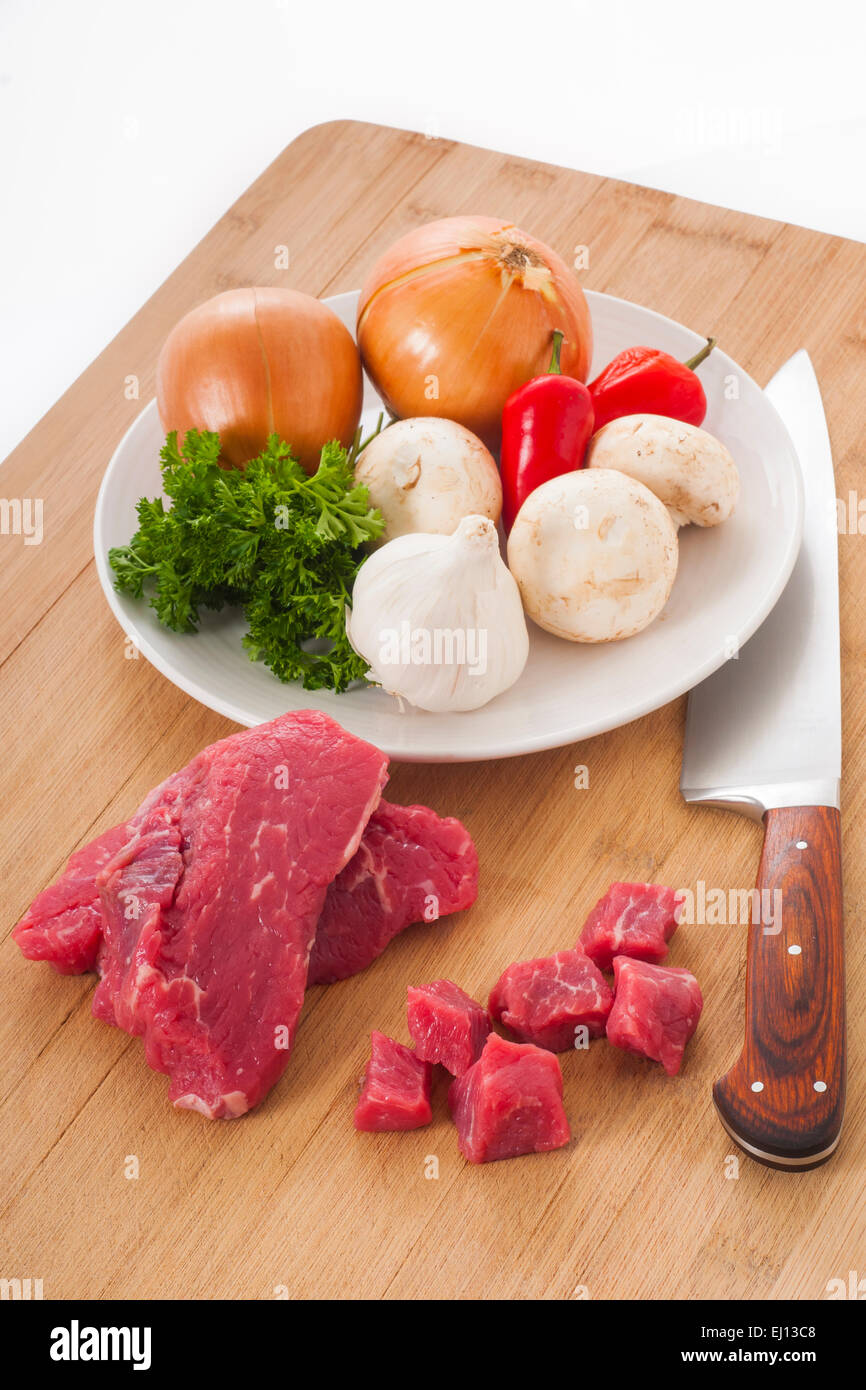 Bistecca di manzo e verdure miste su un tagliere pronto per preparare la cena Foto Stock