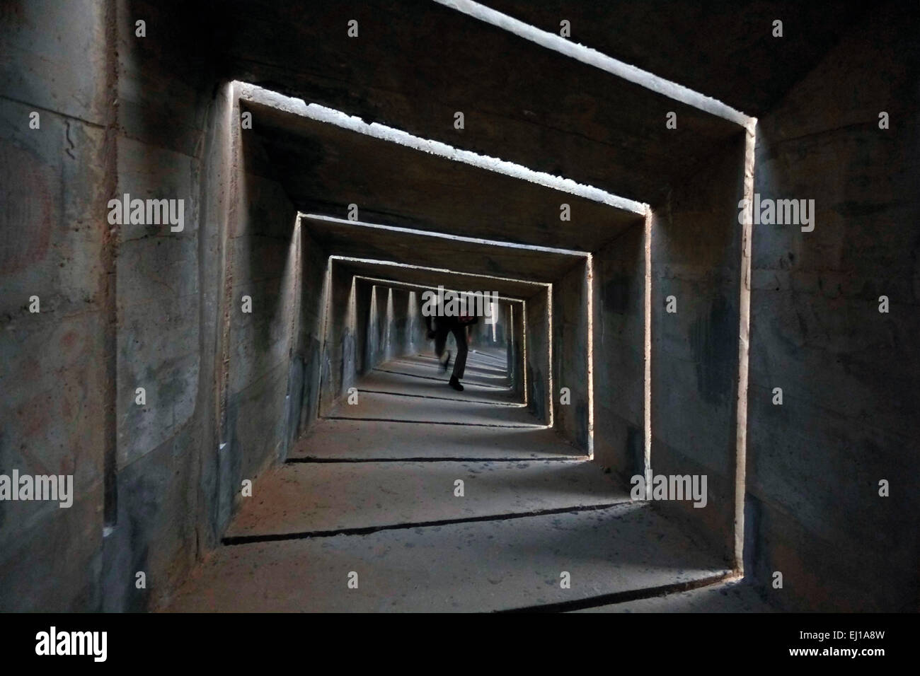Una persona che cammina all'interno del monumento in cemento in stile architettura brutalista alla Brigata Negev conosciuta localmente come l'Andarta progettata da Dani Karavan in memoria dei membri della Brigata Ebraica Palmach Negev che si sono abbattuti in difesa di Israele durante la guerra araba israeliana del 1948. Si trova su una collina che domina Beerseba, anche detto Beer-Sheva, la più grande città nel deserto di Negev nel sud di Israele Foto Stock