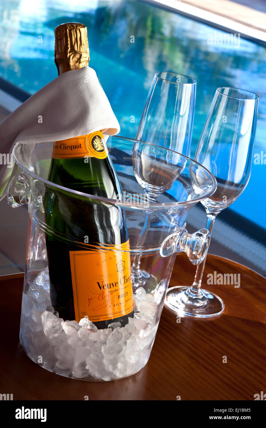 Veuve Clicquot vintage fine bottiglia di champagne con occhiali, su ghiaccio in wine cooler, lusso soleggiata piscina infinity dietro Foto Stock