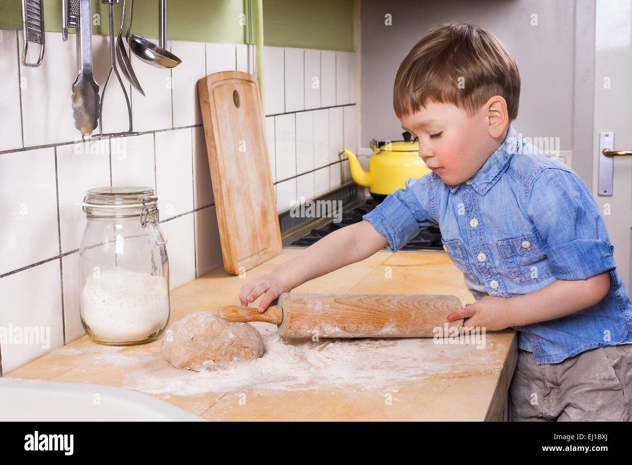Carino il toddler in piedi la cucina con un mattarello e pasta. Foto Stock