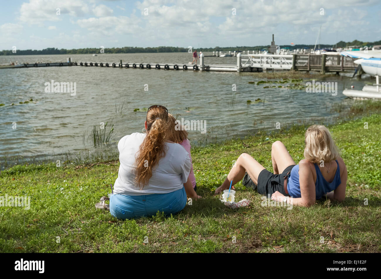 Due ragazze e un bambino rilassarsi sul prato in un Dragon Boat Show in Tavares, Florida USA Foto Stock