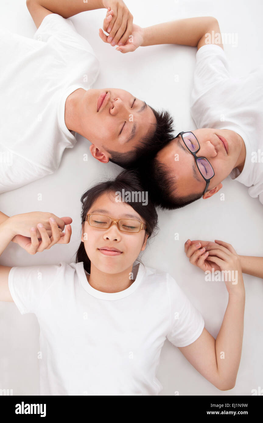 Gli adolescenti sdraiato sulla schiena e tenendo le mani con gli occhi chiusi insieme Foto Stock