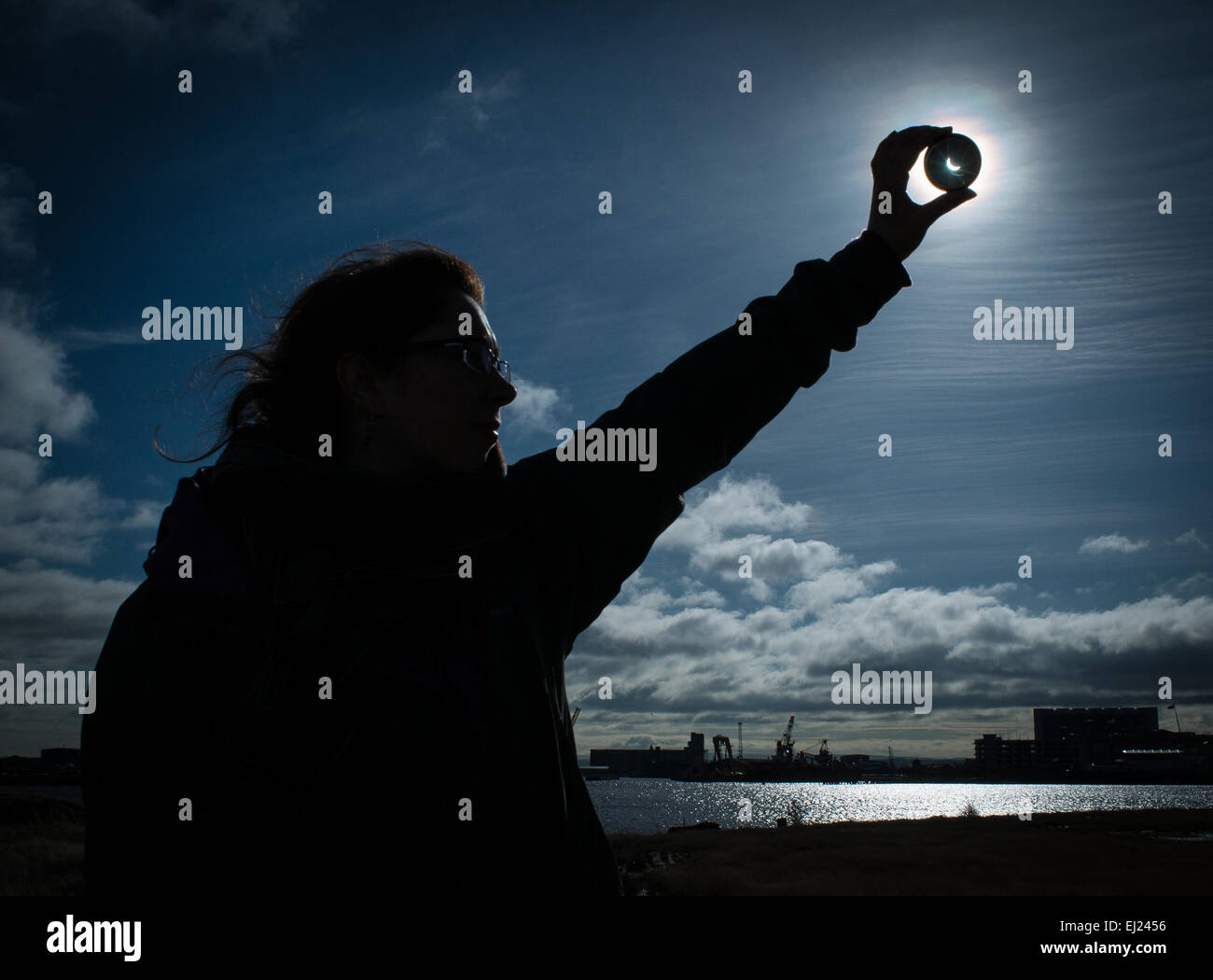 Una signora contiene un filtro di fronte alla parziale eclissi solare, Leith, Edimburgo, Scozia, Marzo 2015 Foto Stock