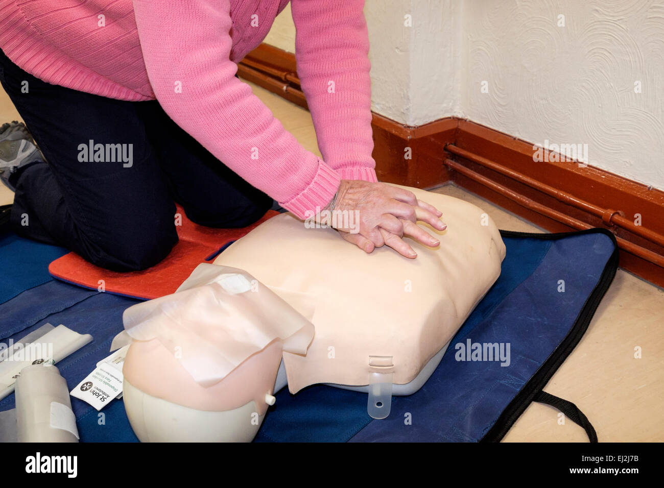 Donna primo aiutante che pratica dare compressioni toraciche CPR usando due mani su un manichino manichino manichino manichino manichino durante un corso di ambulanza di San Giovanni in primo soccorso. REGNO UNITO Foto Stock