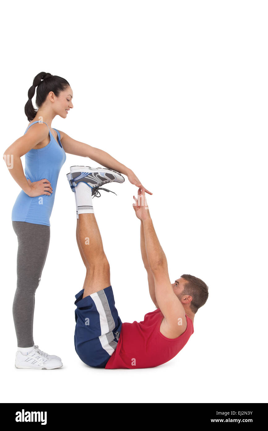Trainer aiutando il suo cliente allungare le gambe Foto Stock