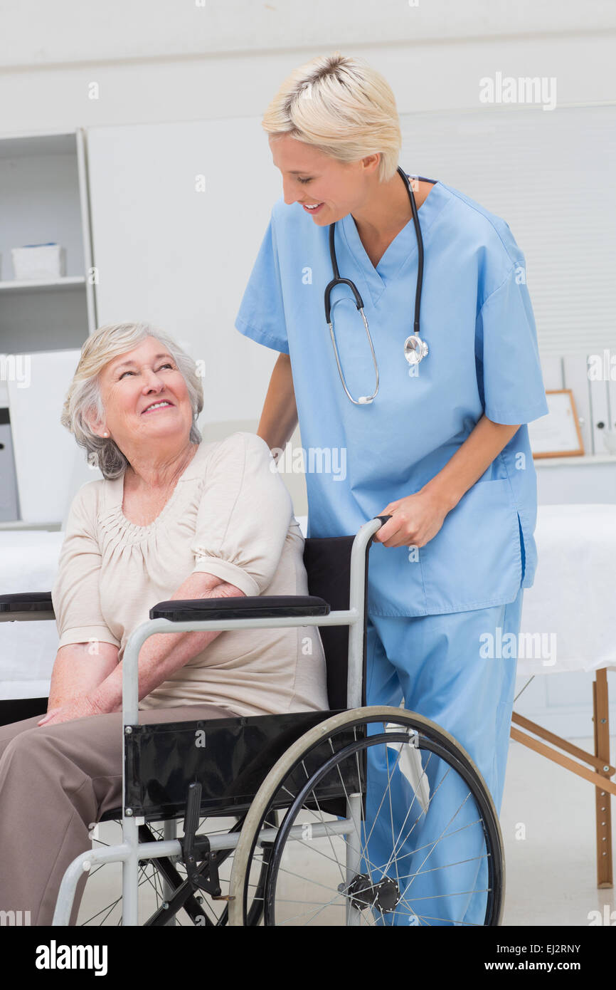 L'infermiera guardando senior paziente seduto su una sedia a rotelle Foto Stock
