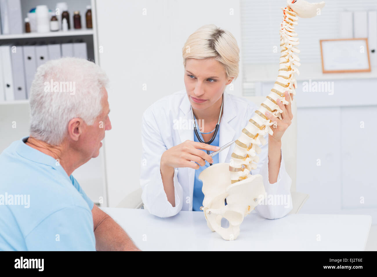 Medico spiegare il modello della colonna vertebrale al paziente senior Foto Stock