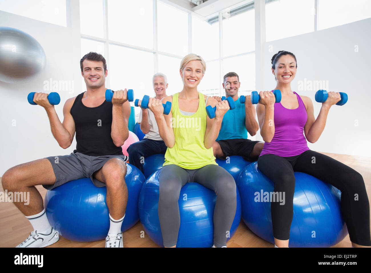 Le persone sedute a sfere e sollevamento pesi nel fitness club Foto Stock