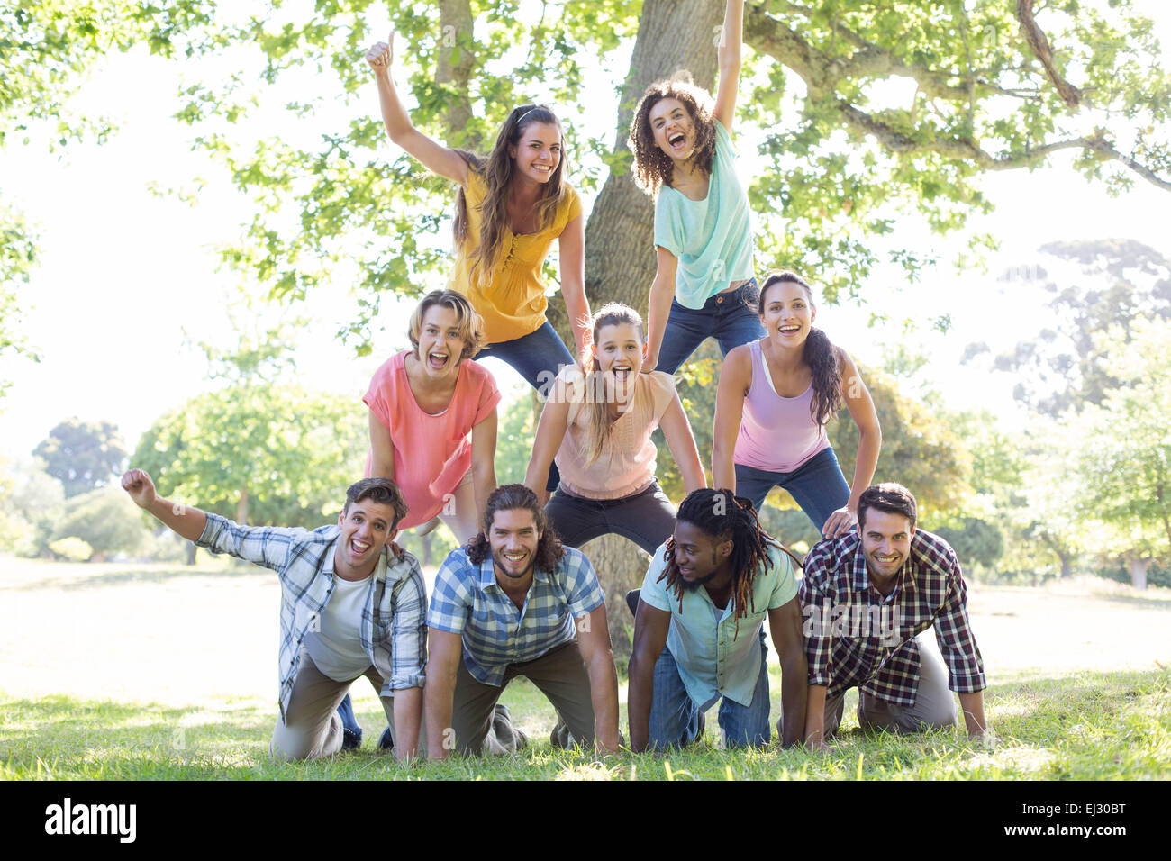 Happy amici nel parco rendendo piramide umana Foto Stock
