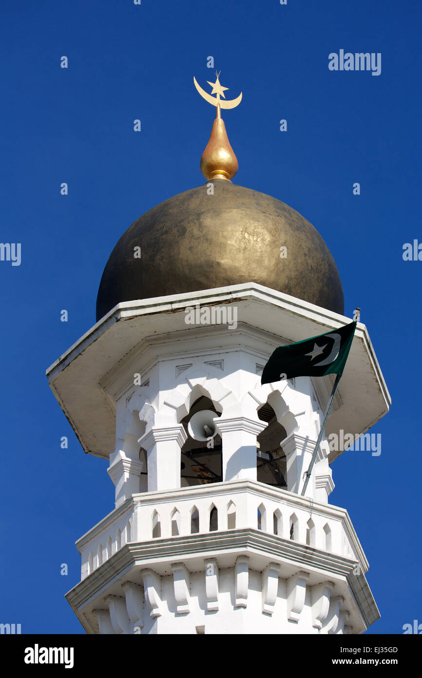 Rame minareto a cupola contro un cielo blu. Stella iconica e Luna in oro sopra riflettono la luce del sole. Bandiera al vento. Foto Stock