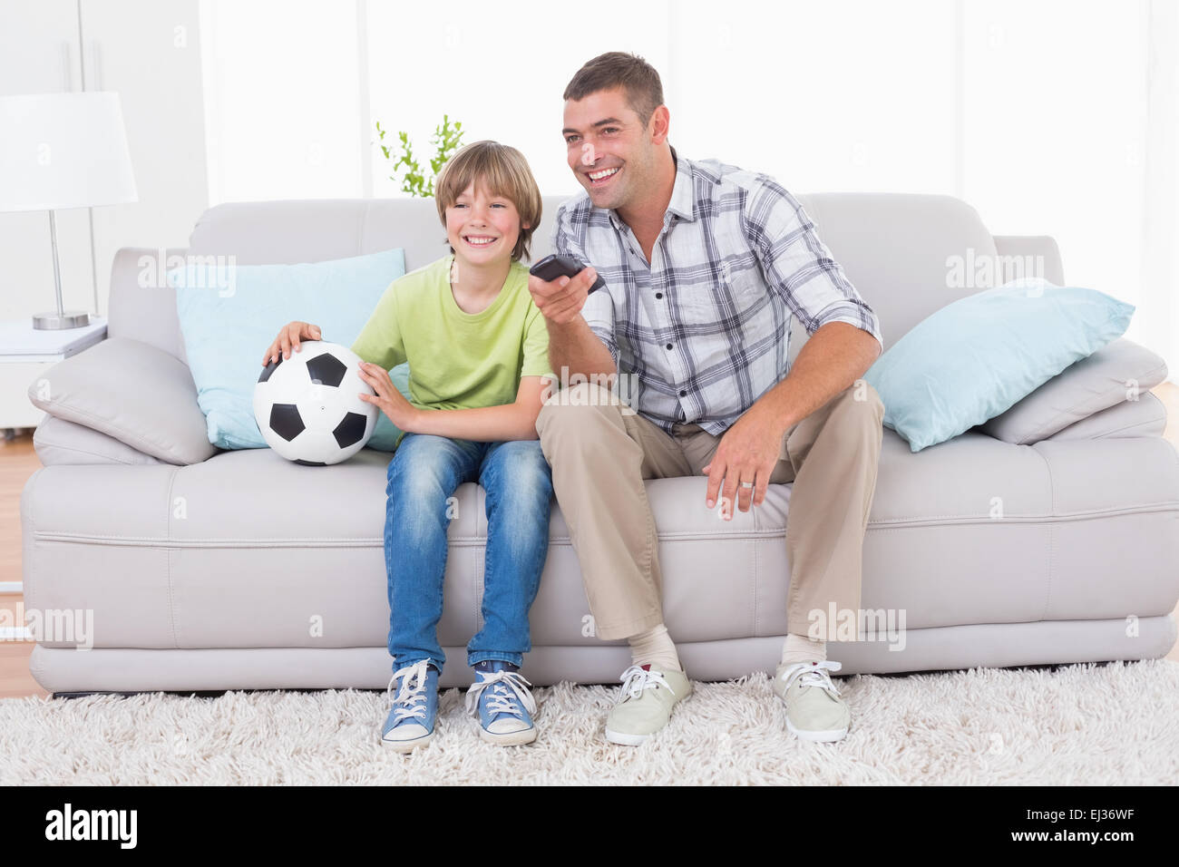 Padre e figlio guardando la partita di calcio sul divano Foto Stock