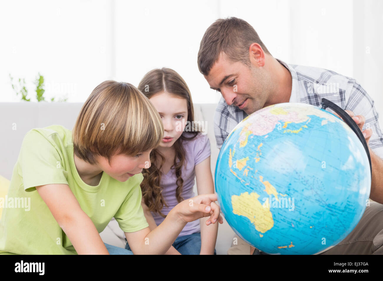 I bambini ad esplorare globe seduti con il padre Foto Stock