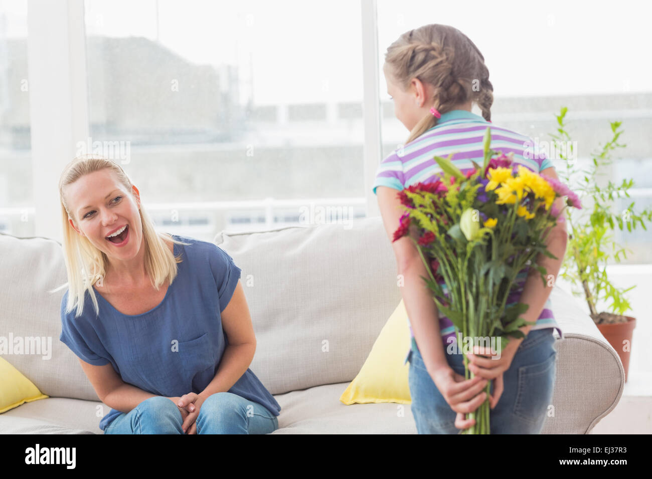Sorpresa madre guardando ragazza nascondendo bouquet Foto Stock