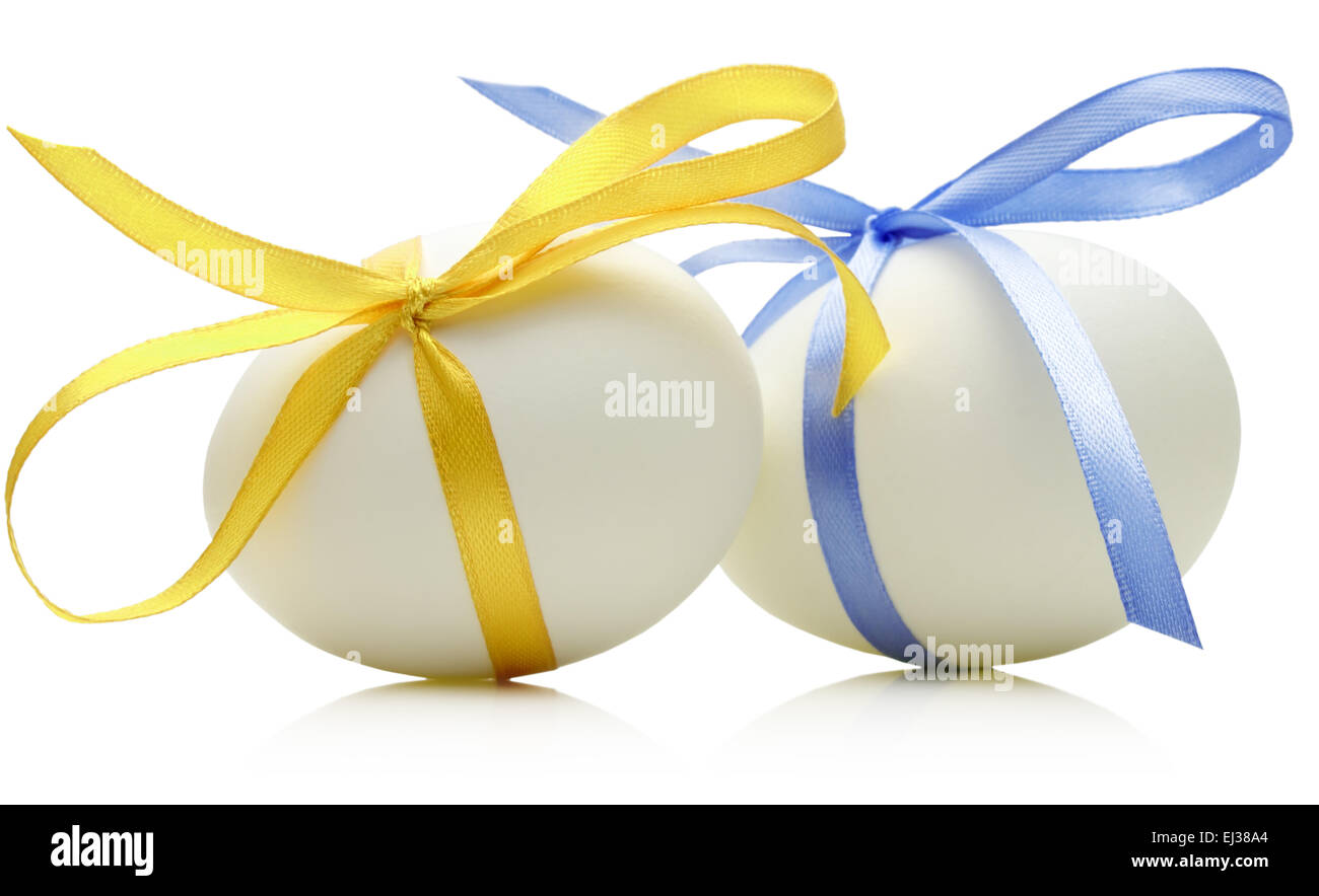 Due uova di Pasqua con la festosa di colore blu e giallo bow isolati su sfondo bianco. Foto Stock