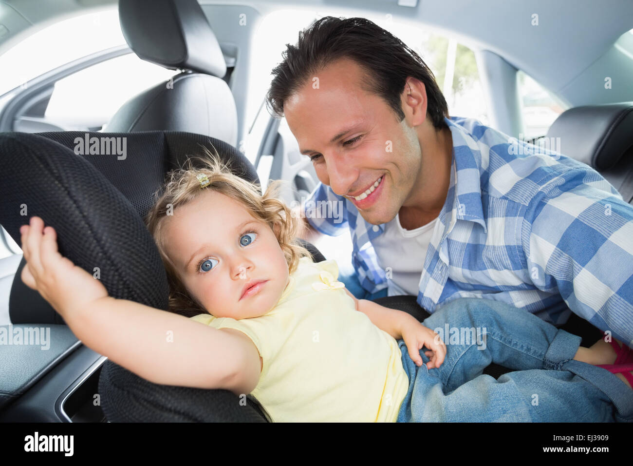 Padre che fissano il suo bambino nel seggiolino per auto Foto Stock