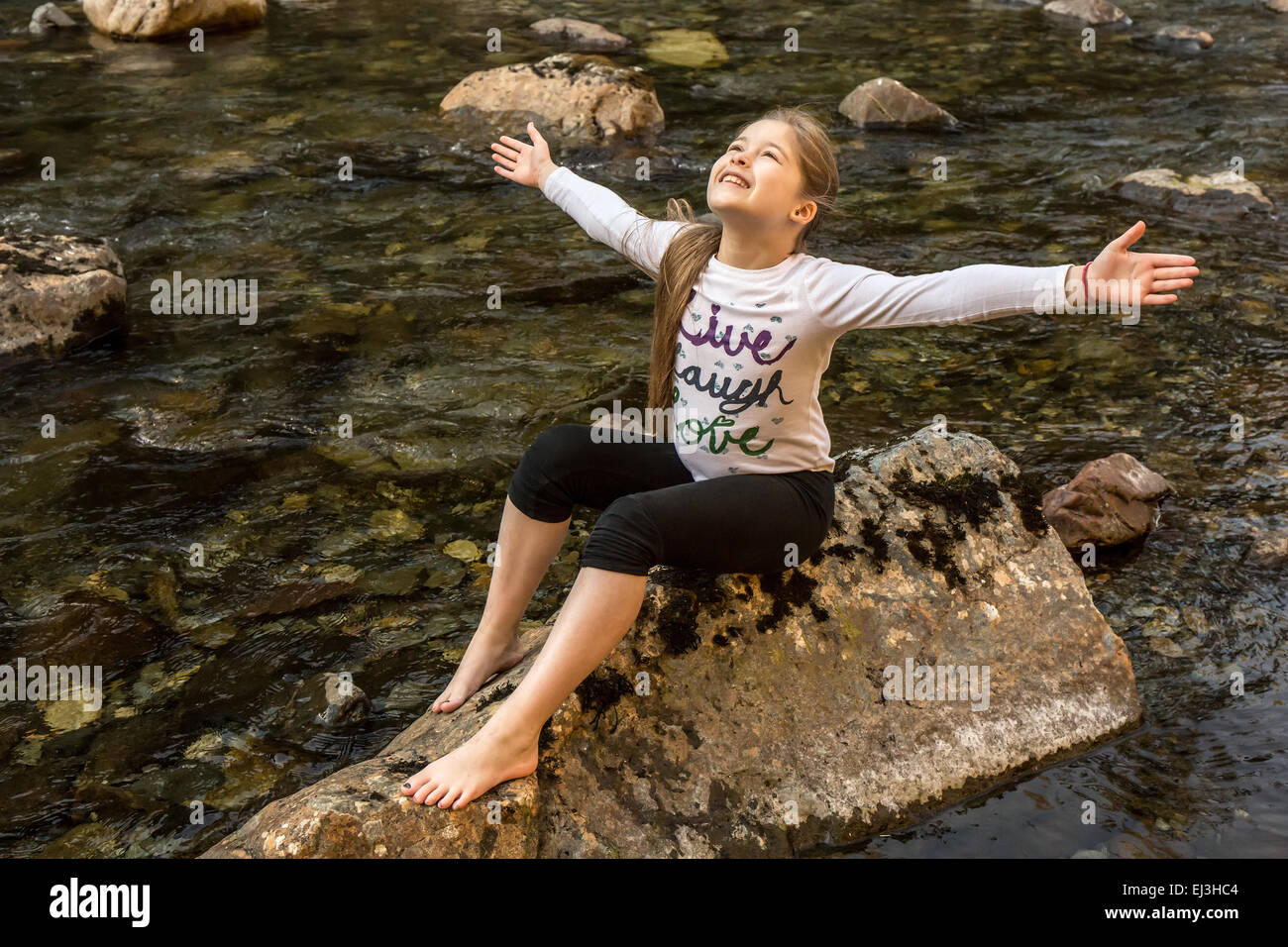 9 anno vecchia ragazza con entusiasmo e con gioia gettando le braccia fuori ampia, nel fiume Snoqualmie in North Bend, Washington Foto Stock