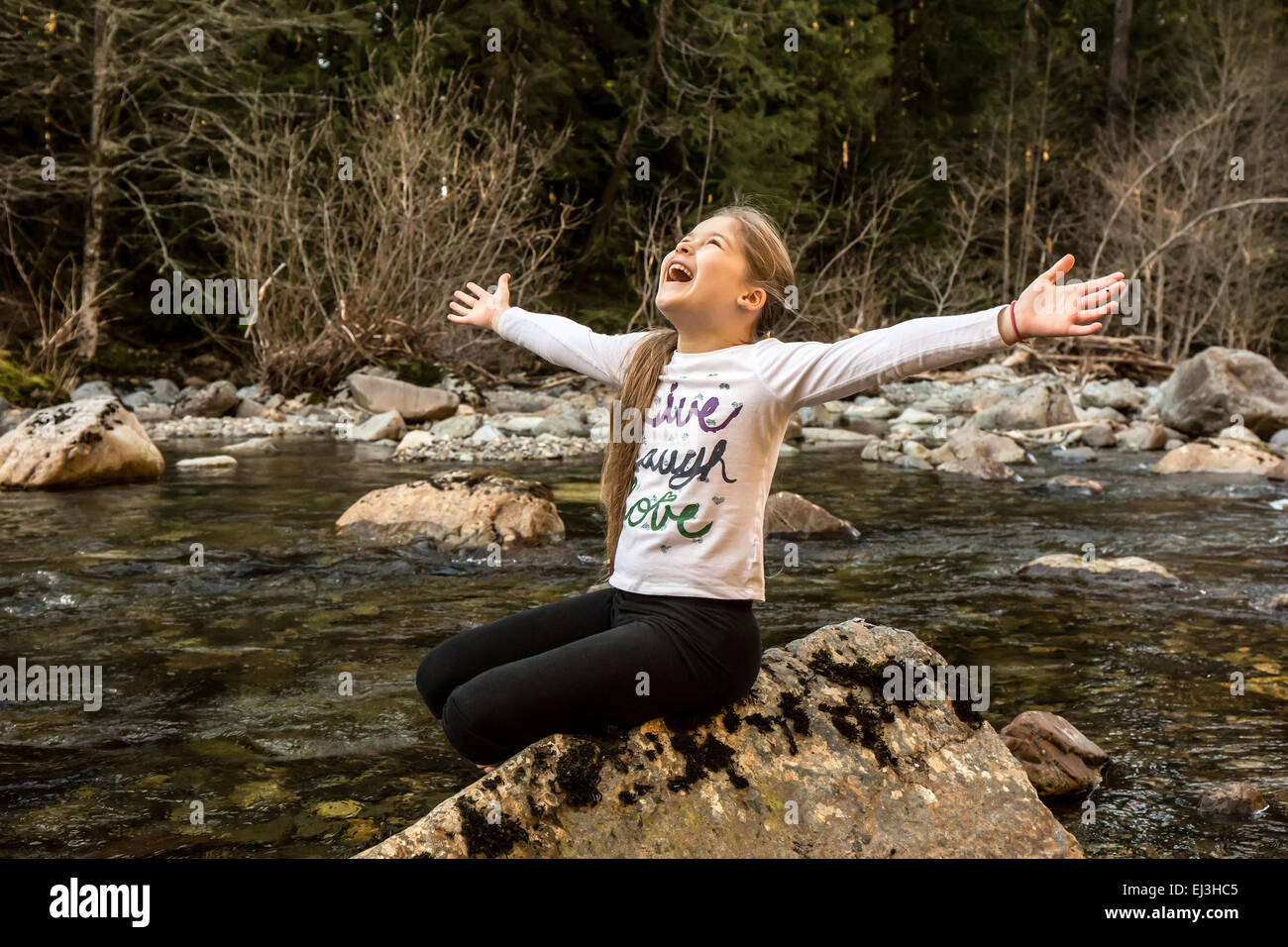 9 anno vecchia ragazza con entusiasmo e con gioia gettando le braccia fuori ampia, nel fiume Snoqualmie in North Bend, Washington Foto Stock