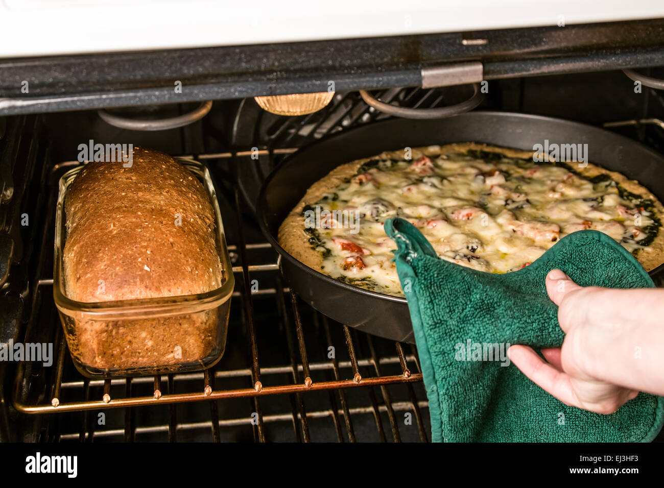 Vegetariano, pesto, multi-grano, spessa crosta di pizza la cottura in forno insieme con un multi-granella della pagnotta di pane fatto con lo stesso Foto Stock