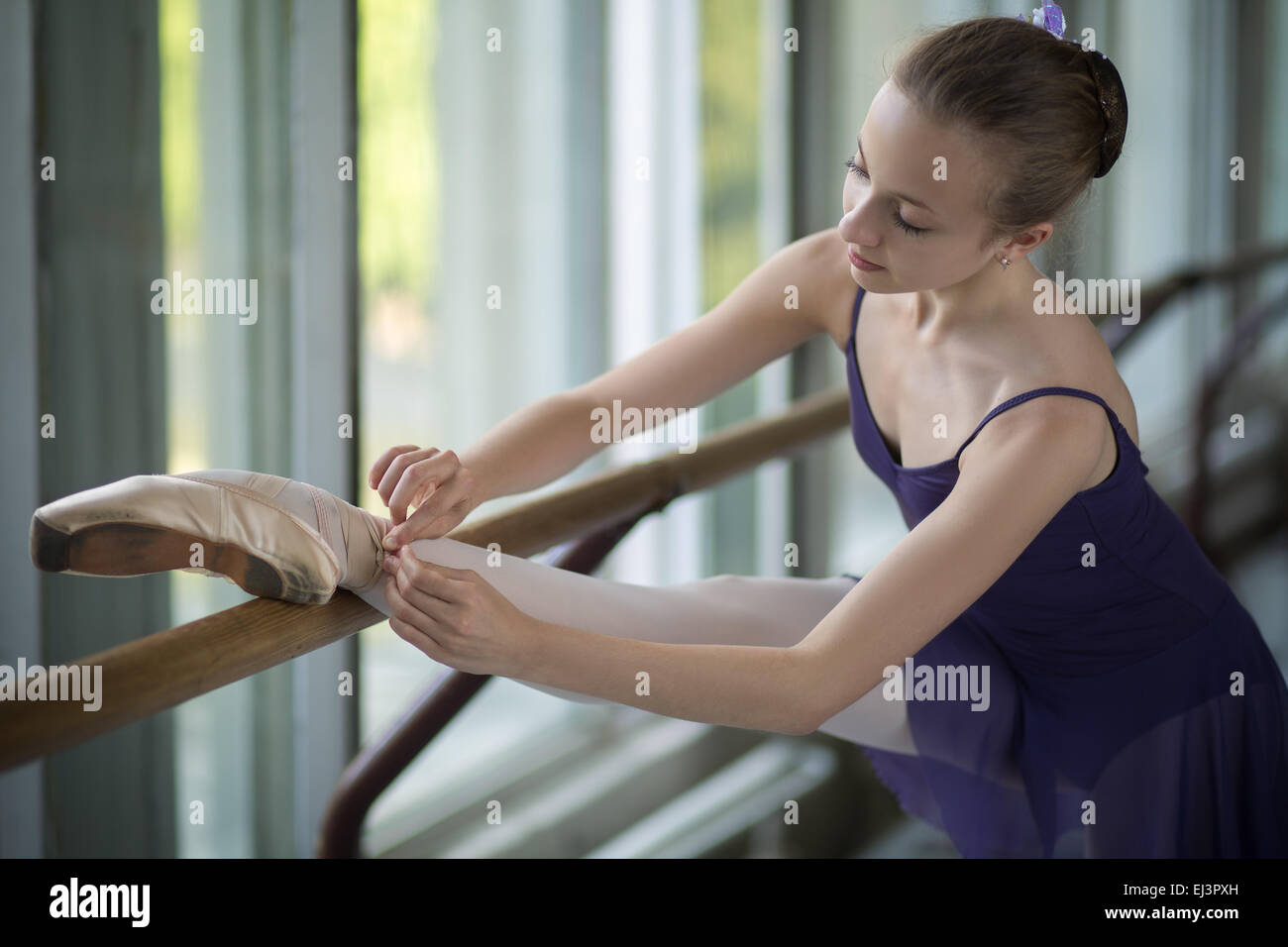 Giovane ballerina in piedi vicino alla finestra, nastri di legatura del punto Foto Stock