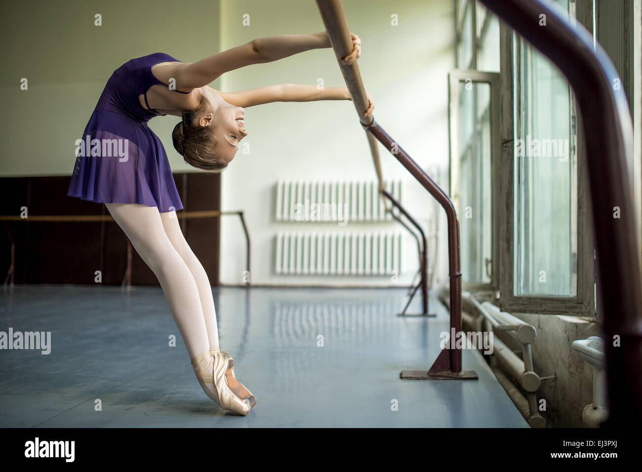 Giovane ballerino facendo un allenamento in aula vicino a barre. Stretc Foto Stock