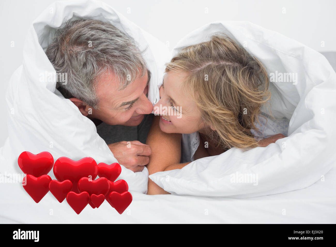 Immagine composita di amorevole coppia di mezza età sotto il piumino Foto Stock