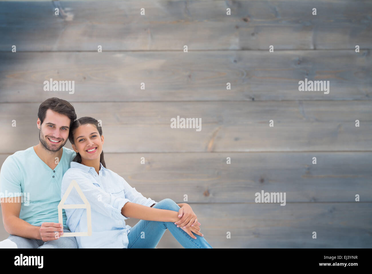 Immagine composita di carino coppia seduta tenendo una casa forma Foto Stock