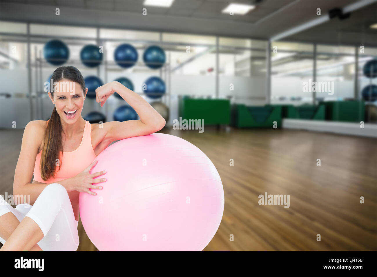 Immagine composita di allegro montare donna flettendo i muscoli dalla sfera di fitness Foto Stock