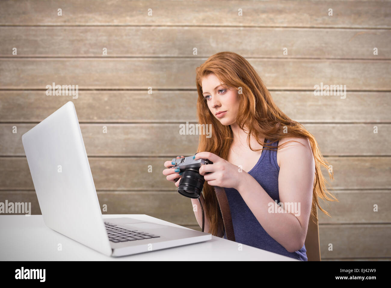 Immagine composita di pretty redhead lavorando sul computer portatile e fotocamera Foto Stock