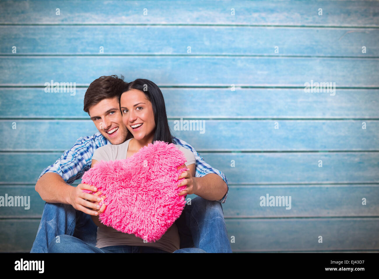 Immagine composita della coppia giovane seduto sul pavimento sorridente Foto Stock