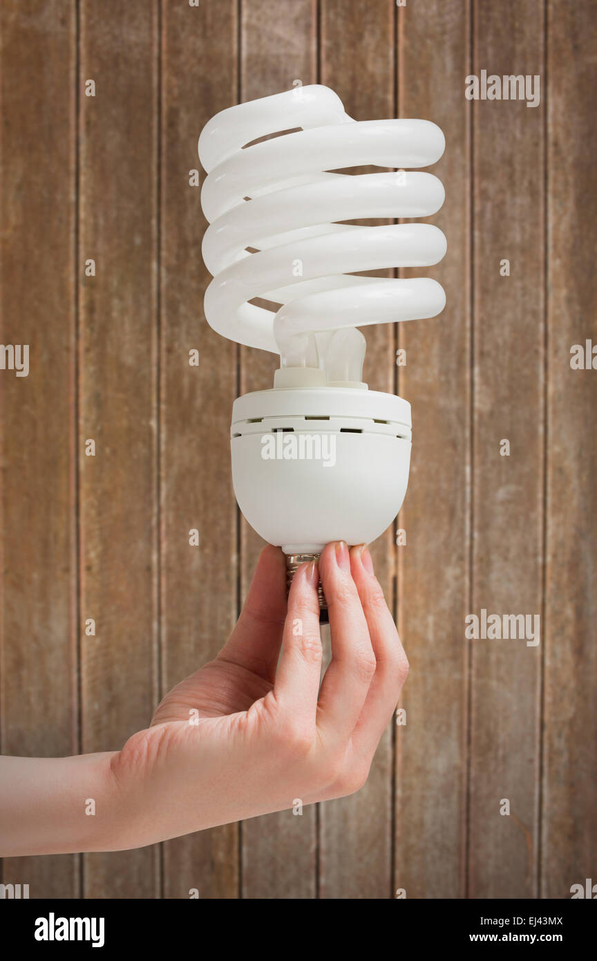 Immagine composita della mano che tiene l'energia efficiente lampadina della luce Foto Stock