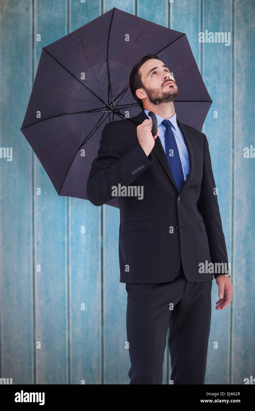 Immagine composita di imprenditrice in tuta tenendo un ombrello mentre guardando in alto Foto Stock