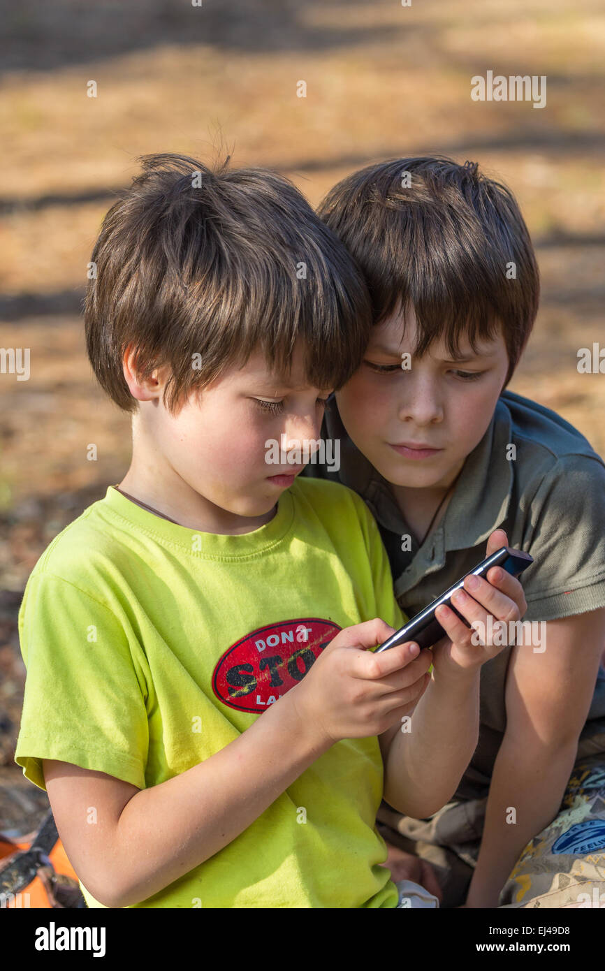 Bambini due ragazzini la riproduzione cellulare all'aperto Foto Stock