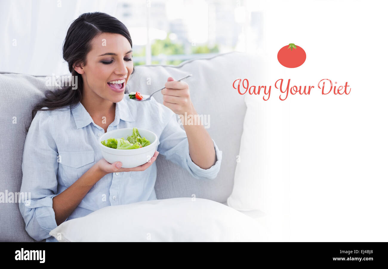 Variare la vostra dieta contro la donna felice rilassante sul divano a mangiare insalata Foto Stock