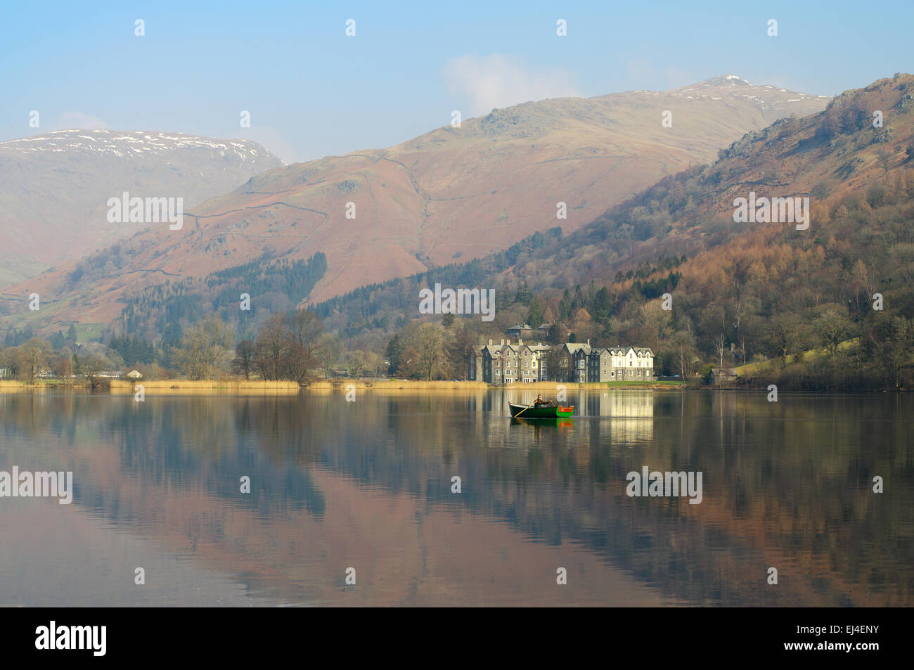 Il Daffodil Hotel si riflette nel lago di Grasmere, dell'uomo con la barca a remi, Lake District, England, Regno Unito Foto Stock