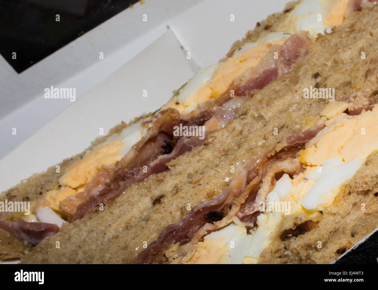 Shop comprato uova e bacon in sandwich di pane integrale, uneaten e ancora in imballaggi di cartone ma aperto. Foto Stock