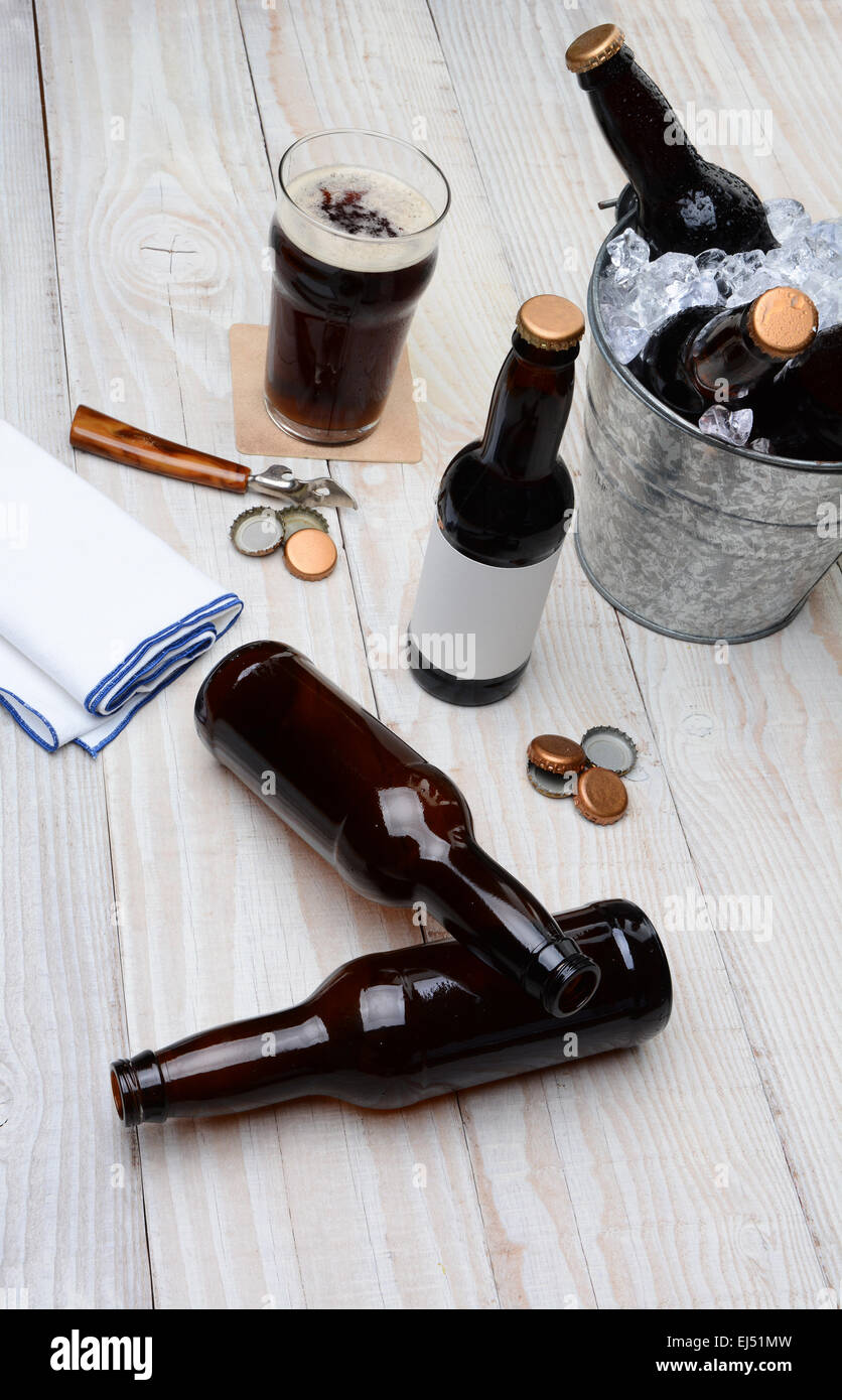 Alta angolazione di un partito benna riempita con bottiglie di birra su una tavola in legno rustico. Le bottiglie vuote e i tappi di bottiglia sono sul tabl Foto Stock