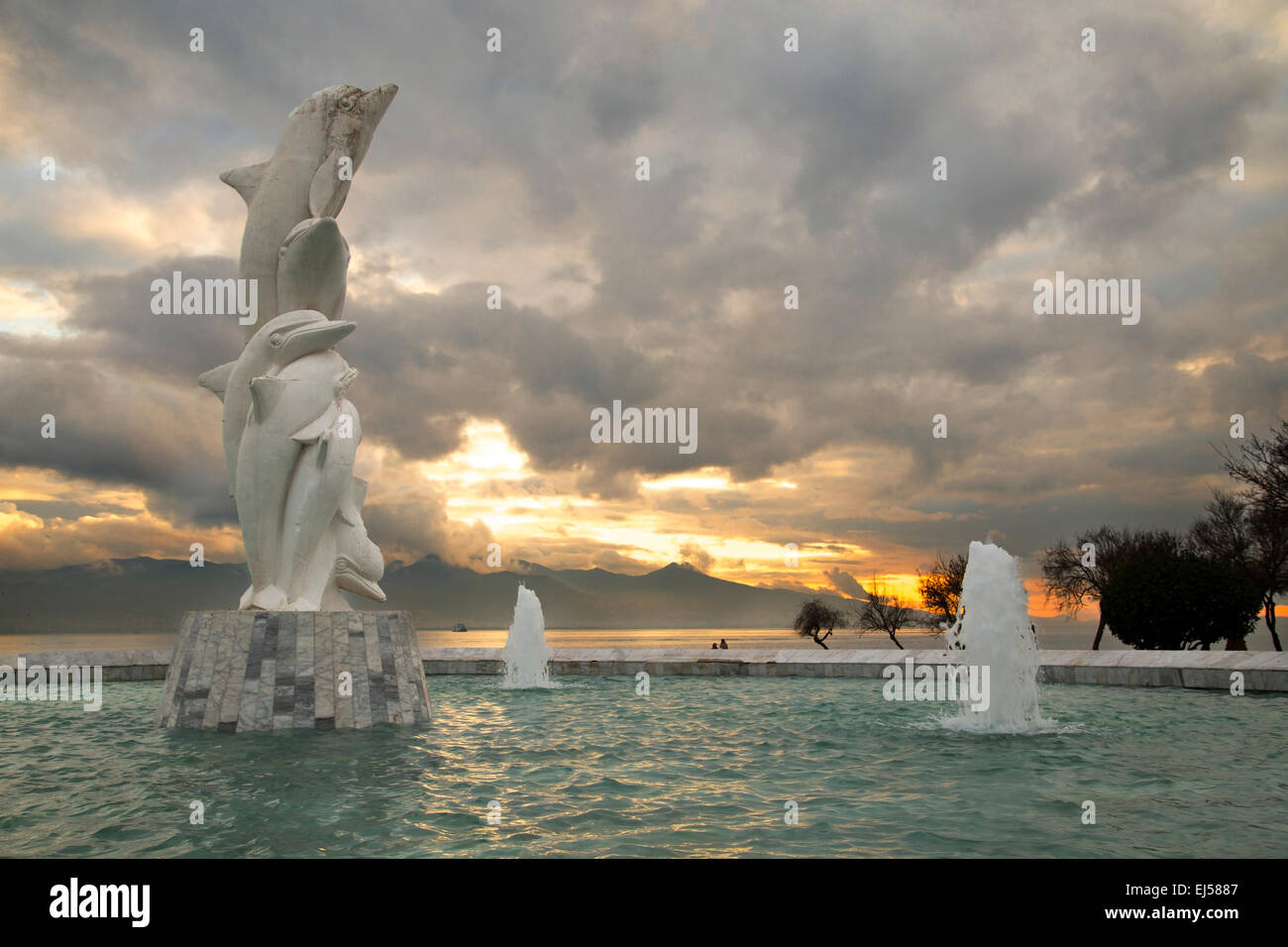 Famosa Dolphin statua in uno stagno con uno sfondo con cielo nuvoloso durante il tramonto in Karsiyaka Izmir, Foto Stock