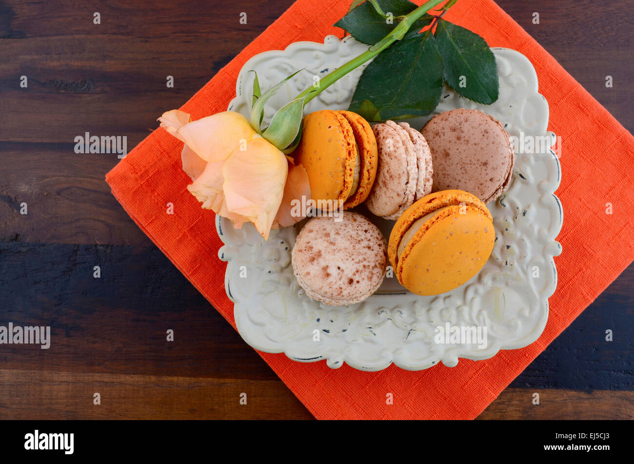 Caramello e vaniglia amaretti in ciotola vintage su Orange e legno scuro impostazione tabella. Foto Stock