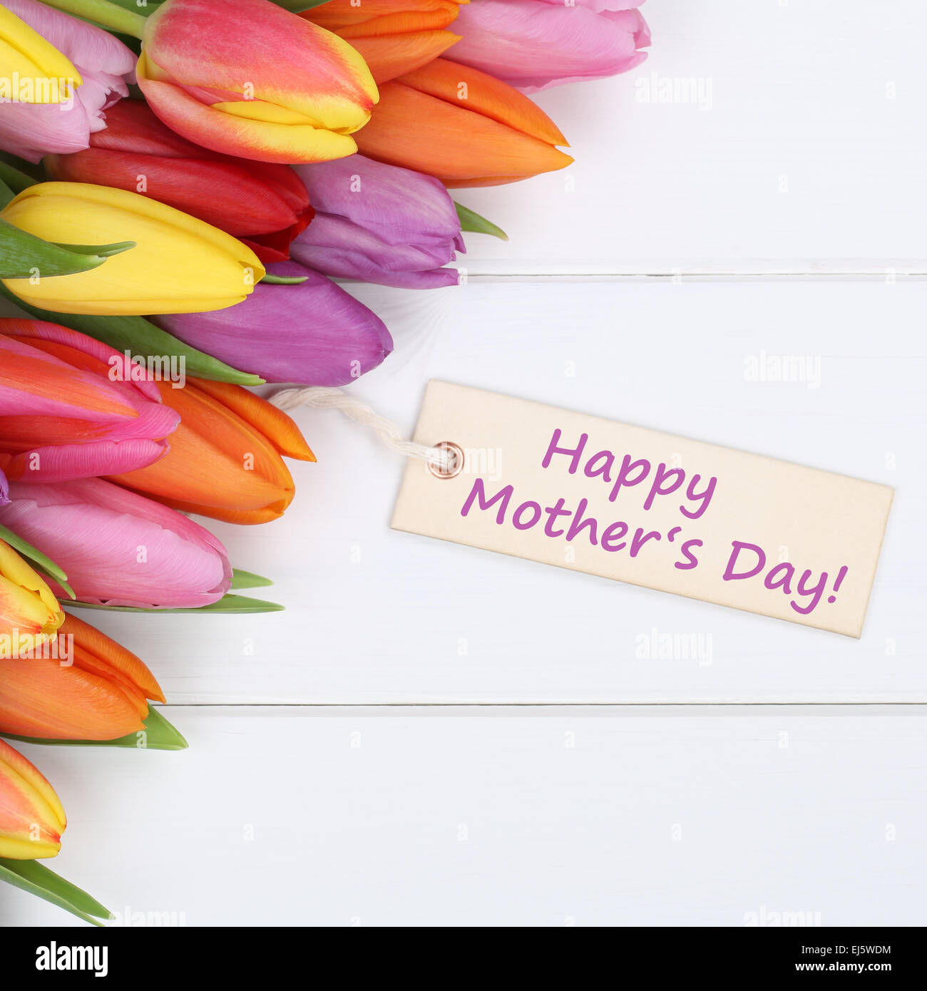 Felice giorno della madre con tulipani colorati fiori su un bianco tavola di legno con biglietto di auguri Foto Stock