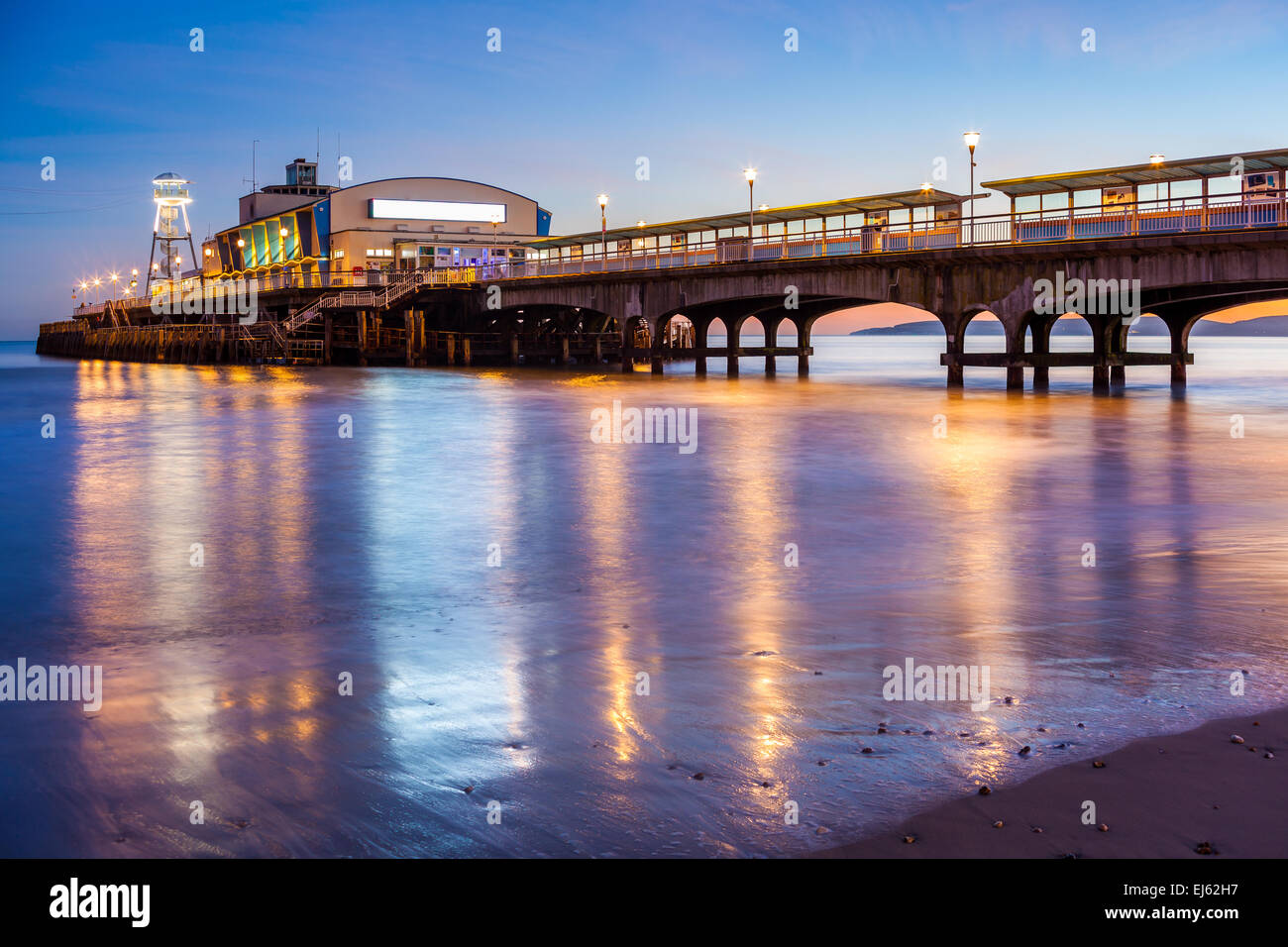 Le luci del molo di Bournemouth di notte si riflette nella sabbia bagnata sulla spiaggia. Il Dorset England Regno Unito Europa. Foto Stock