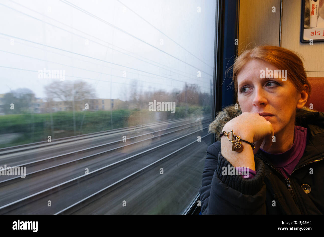 Una donna guarda fuori dalla finestra di un treno guardando triste. Foto Stock