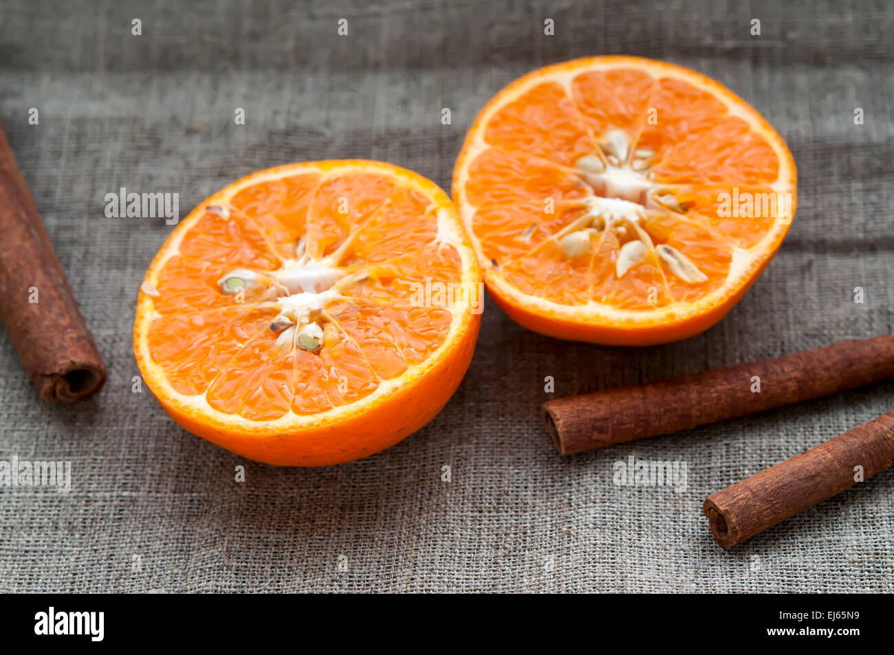 Set di frutta - arancio mandarino metà e bastoncini di cannella in Assia Biancheria panno in tessuto Foto Stock